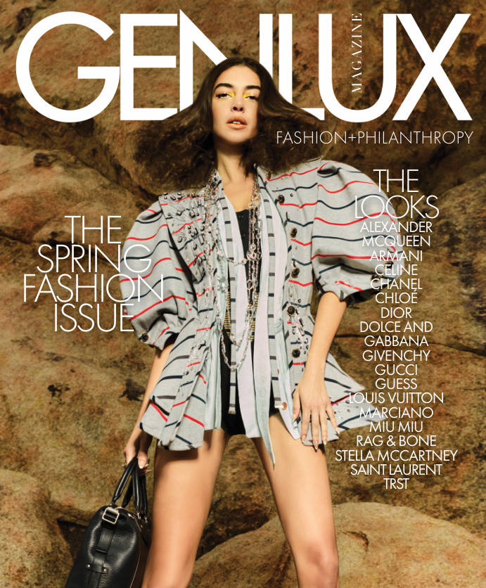 Magazine cover featuring a model in a gray striped jacket holding a handbag, against a stone backdrop.